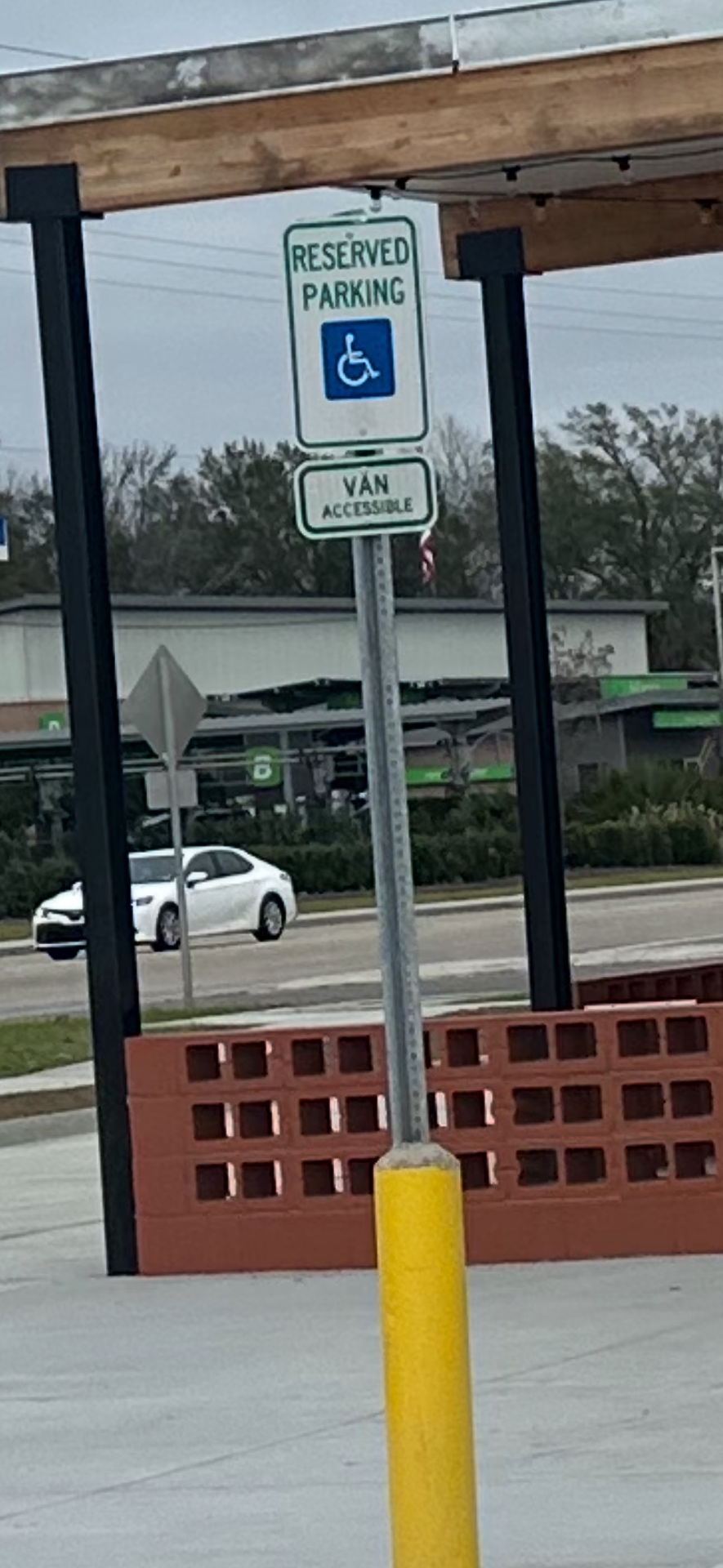 Reserved accessible and van-accessible parking sign installed above a yellow bollard