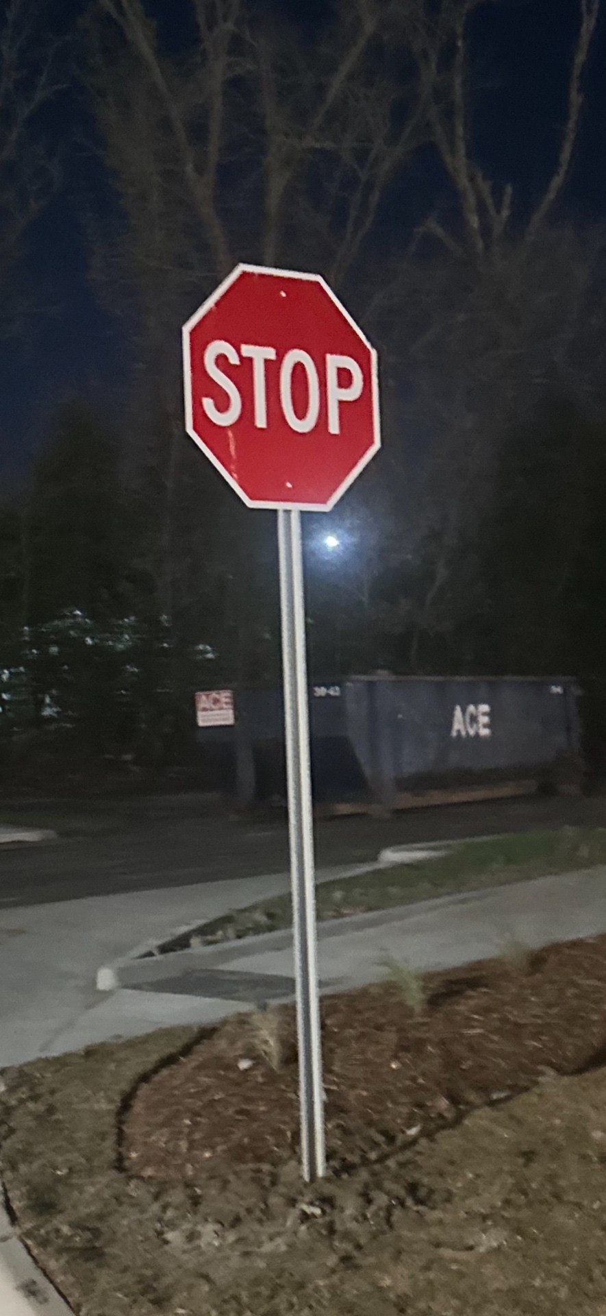 New stop sign installed beside a commercial parking area at night