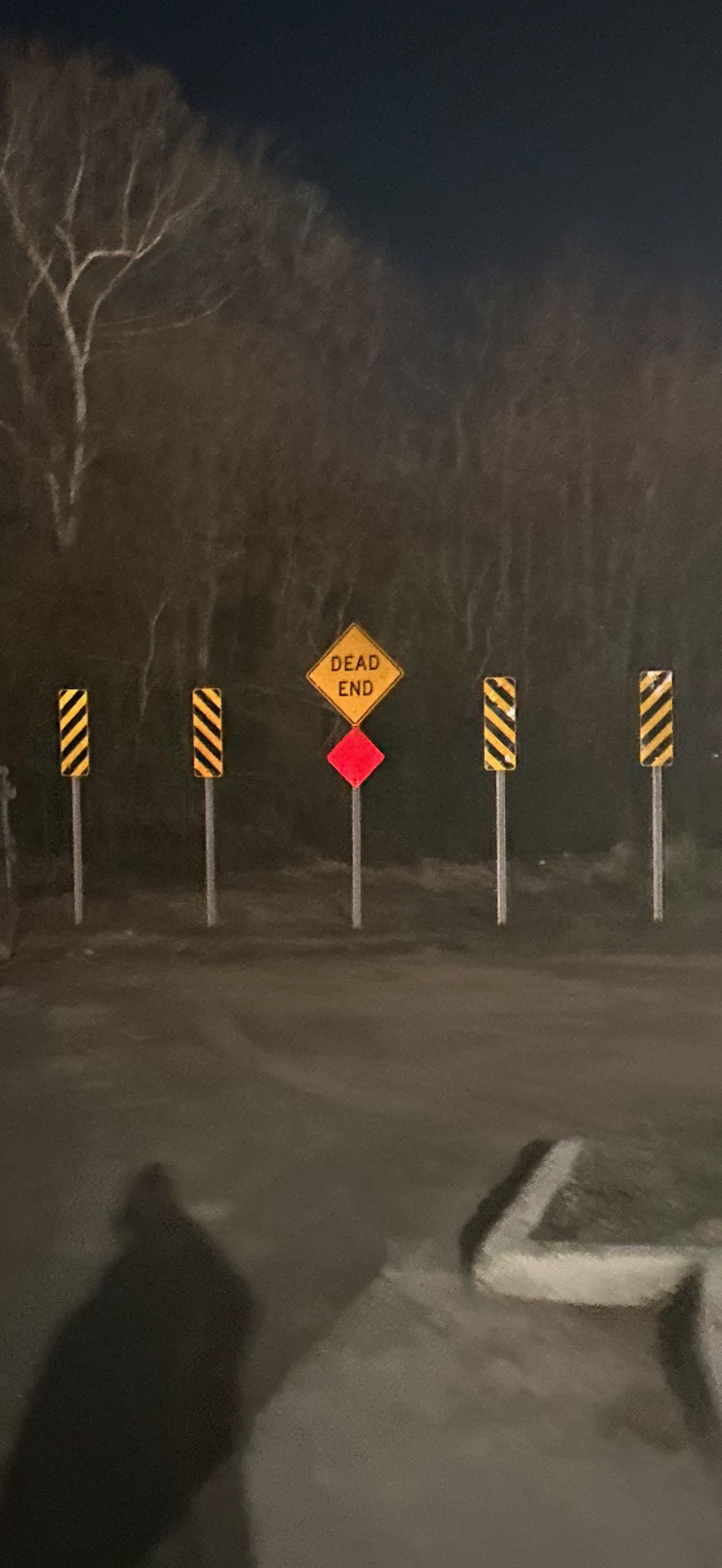 Dead end sign and striped hazard markers installed at the end of a parking lot
